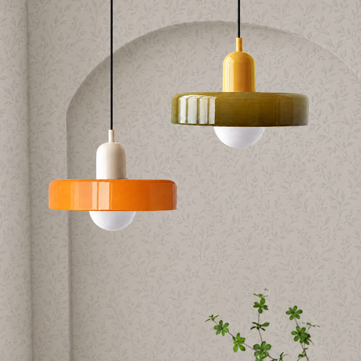 Orange and olive Bauhaus glass disc pendant lights against light grey botanical wallpaper with an arch
