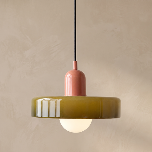 Olive glass disc pendant light with pink top against a warm beige limewash wall