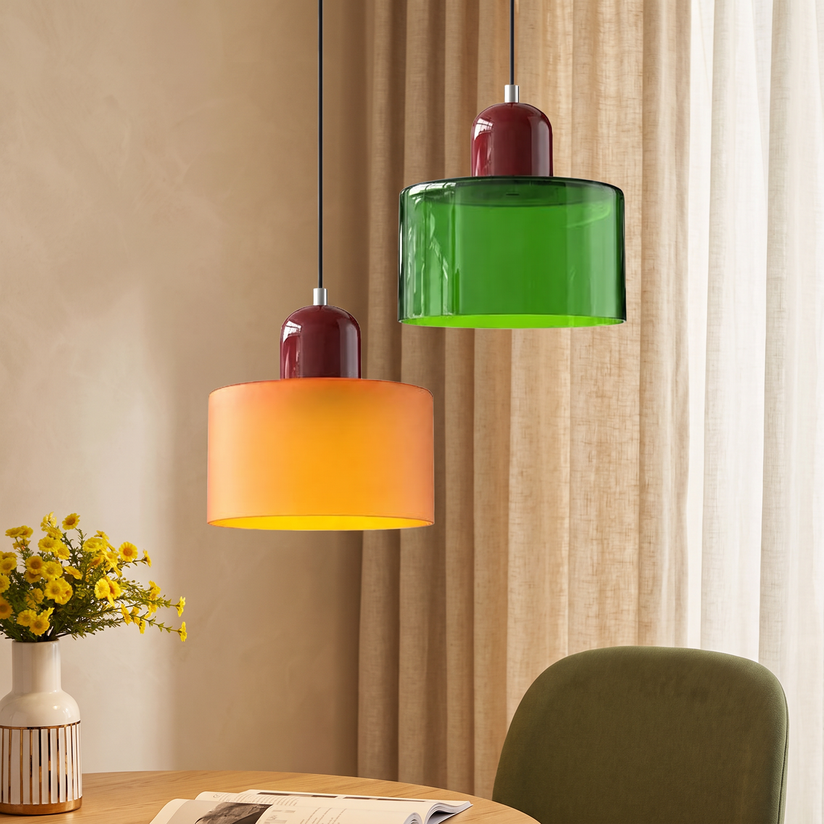 Orange and green glass drum pendant lights with burgundy tops above an oak table with an olive green chair