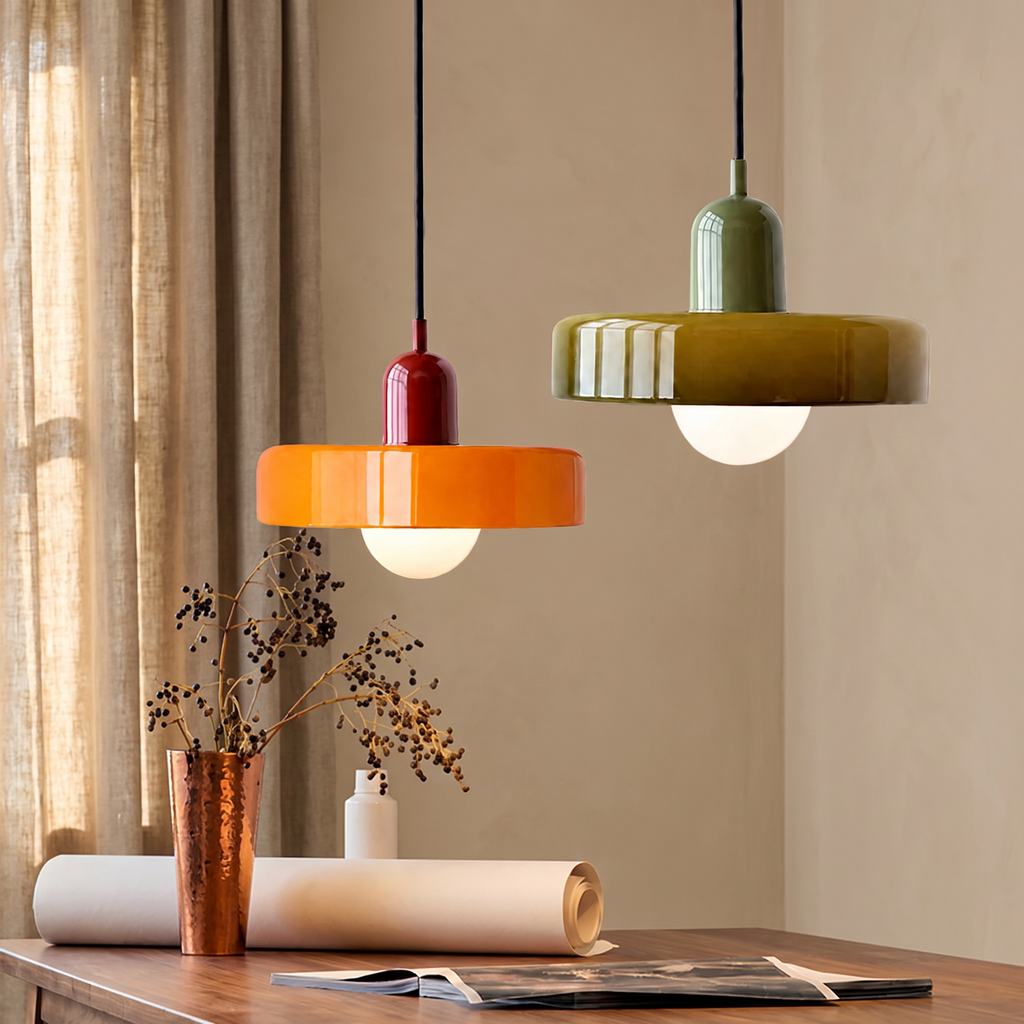 Orange and olive glass disc pendant lights above a desk against a warm beige wall with linen curtains