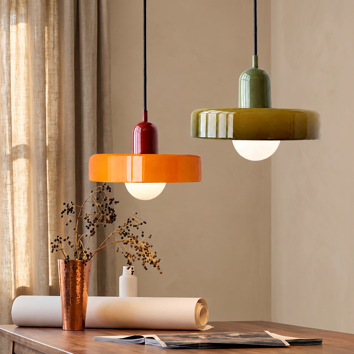 Orange and olive glass disc pendant lights above a desk against a warm beige wall with linen curtains