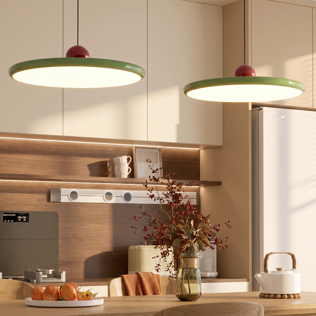 Two green saucer LED pendant lights with red spheres in a kitchen with warm cream cabinets and oak shelves