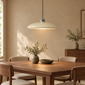 Cream saucer pendant light with silver sphere above a walnut dining table in a warm beige room