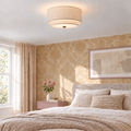 Two-tier linen drum ceiling light in a bedroom with warm patterned wallpaper