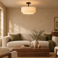 Double drum semi-flush linen ceiling light glowing above a linen sofa in a warm living room